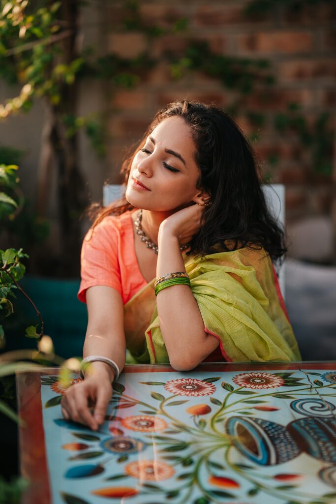A serene portrait of a woman in a colorful saree, enjoying a peaceful moment outdoors.